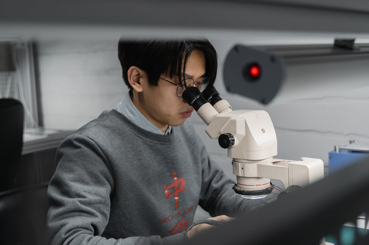 A man using a microscope for scientific research in a laboratory setting.